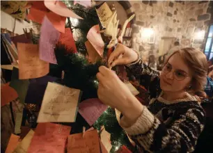  ?? AFP ?? A Syrian youth hangs on a Christmas tree New Year wishes written on a card in the Zeriab coffee shop in Damascus on Sunday. —