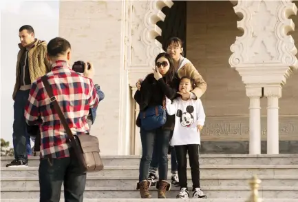  ??  ?? Asian tourists pose for a photo as they visit the Hassan Tower in Rabat. (AFP)
