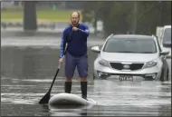 ?? (AP/Mark Baker) ?? A man paddles on a stand-up paddle board through a flooded street Tuesday in Windsor, Australia.