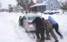  ?? AP ?? Neighbours help push a motorist stuck in the snow in Buffalo, New York, on Monday.