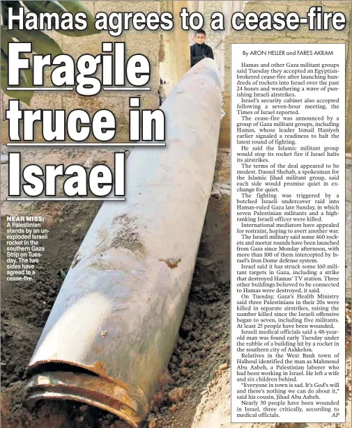  ??  ?? A Palestinia­n stands by an un exploded Israeli rocket in the southern Gaza Strip on Tues day The two sides have agreed to a cease-fire. NEAR MISS: