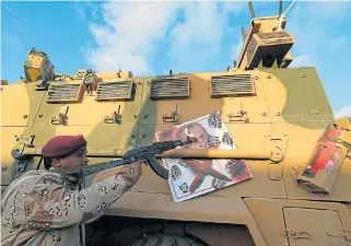  ??  ?? Respite:
A member of the Libyan National Army points his gun next to the image of Turkish President Recep Tayyip Erdogan. The coronaviru­s outbreak has, however, not ended conflicts in many parts of the world.