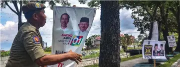  ??  ?? A member of Indonesia’s Public Order Service (Satpol PP) takes down election campaign banners in Pekanbaru following the end of the campaignin­g period ahead of the April 17 polls. — AFP photo