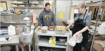  ?? TROY FLEECE ?? Sacred Heart School principal Dave Magnusson collects a cart of prepared food from cook Ruth Munro to take to students as part of the school’s lunch program. Community partners help support the program.