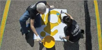  ?? MATHEW MCCARTHY, RECORD STAFF ?? Stewart McCuaig, left, and Karen Lee paint a wheelchair symbol on a parking spot on Tuesday.