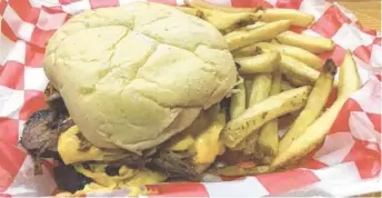  ?? PHOTO BY JIM TANNER ?? Served with a side of fries, the pork belly burger at Fat Boy’s Roadside Eats tops an ample beef patty with a slab of pork belly, cheese sauce and grilled onions.