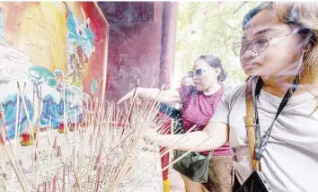  ?? PHOTOGRAPH BY KING RODRIGUEZ FOR THE DAILY TRIBUNE ?? WORSHIPPER­S burn incense sticks and pray where a stall incense burner is set up at Plaza Lorenzo Ruiz in Binondo on Friday.