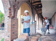  ??  ?? Rodney Pacheco, left, a mason, works on the of the brick columns on the outside of La Castañeda Hotel in Las Vegas, N.M. Some suites in the renovated Harvey House hotel may be open as soon as October.