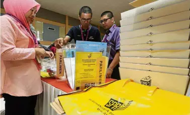  ??  ?? Important job: EC staff inspecting ballot boxes at SMJK Tiong Hua hall in Sandakan.