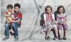  ?? — AFP ?? Syrian children pose for a photo near their house in the rebel-held town of Douma, on the eastern outskirts of Damascus, on Saturday.