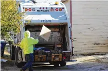  ?? CORNELIUS FROLIK / STAFF ?? A waste collection worker throws trash into the back of a trash truck.