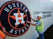  ??  ?? Earlier this year, workers with Donnie Bennett Lighting install a sign outside the Houston Astros clubhouse. Some companies think the county hasn’t done enough to help them.