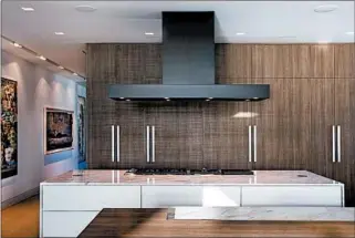  ?? PAUL STOPPI/DUNAGAN DIVERIO ?? In this Miami Beach kitchen designed by Dunagan Diverio, pale walls display art as the custom appliance fronts and cabinetry create an integrated, serene sightline throughout an open-plan kitchen and living space.