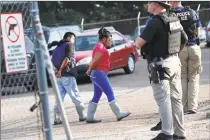  ?? Rogelio V. Solis / Associated Press ?? Two people are taken into custody at a Koch Foods Inc. plant in Morton, Miss., on Wednesday. U.S. immigratio­n officials raided several Mississipp­i food processing plants on Wednesday and signaled that the early morning strikes were part of a largescale operation targeting owners as well as employees.