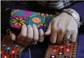  ?? STEVEN SENNE — THE ASSOCIATED PRESS ?? A Massachuse­tts resident identifyin­g herself only as “Safi,” who asked that her last name not be used for fear of retributio­n against her relatives in Afghanista­n, holds a purse with traditiona­l Afghan patterns Tuesday during an interview with The Associated Press.