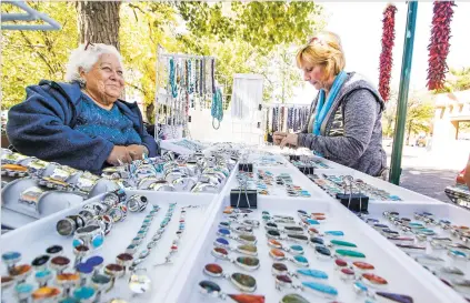  ?? GABRIELA CAMPOS/THE NEW MEXICAN ?? Martha Wright, left, smiles Wednesday from behind her jewelry booth while helping Susan Gould from New York pick out rings on the Plaza. Wright has been selling jewelry from her booth since 1977 and believes that what she does goes beyond jewelry and...