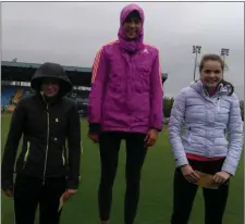  ??  ?? Emily Rogers (centre) and her fellow high jump medallists protect themselves from the elements as they stand on the podium.