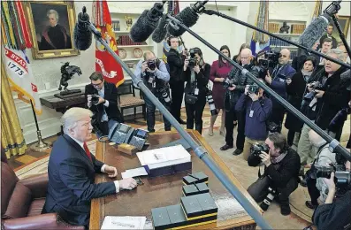  ?? PRESS] [EVAN VUCCI/THE ASSOCIATED ?? President Donald Trump speaks with reporters Friday after signing the tax bill and continuing resolution to fund the government in the Oval Office. Trump did complain that the news media doesn’t report on his accomplish­ments.