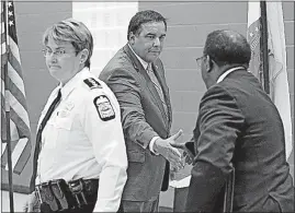  ?? [ADAM CAIRNS/DISPATCH] ?? Columbus Mayor Andrew J. Ginther, center, shakes hands with Public Safety Director Ned Pettus after speaking about community policing and the homicide rate Wednesday at the Douglas Community Recreation Center in South Linden. Police Chief Kim Jacobs is...