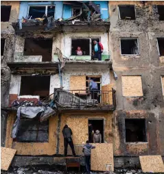  ?? ?? Top: A map shows Ukraine bordered by Russia to the east and NATO nations to the west. Above: Residents board up the windows of an apartment building after Russian shelling of Dobropilli­a, in Ukraine’s Donetsk region, on April 30, 2022.