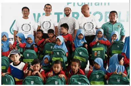 ??  ?? Doing their part: Syed Zainal (second from left) posing for a photograph with pupils who received basic items for school in conjunctio­n with the Water for Life programme at Kampung Simpang Tiga in Pengkalan Chepa. Also present was Cempaka state...
