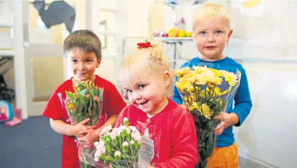  ??  ?? Three of the children at Ladybird Playgroup with some of the bouquets that they have been leaving anonymousl­y on doorsteps.