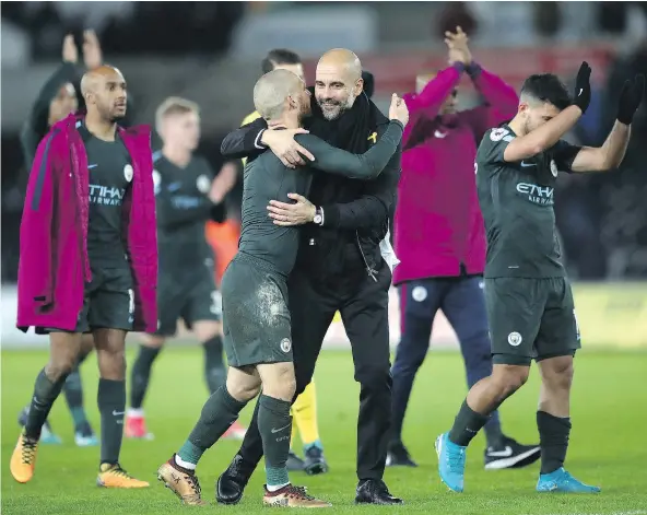  ?? — AP FILES ?? Manchester City manager Pep Guardiola, centre right, gets a victory hug from midfielder David Silva after the final whistle sounded in a 4-0 win over Swansea City on Wednesday. Silva, who scored twice for Guardiola’s unbeaten club, has been a force of...