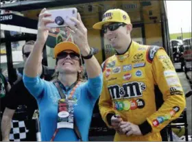  ?? LYNNE SLADKY — THE ASSOCIATED PRESS ?? Kyle Busch, right, poses for a photo with a fan during practice for the NASCAR Cup Series auto race at the Homestead-Miami Speedway, Saturday in Homestead, Fla. Busch was gifted the coveted No. 1 pit stall Saturday when Joe Gibbs Racing made the dubious decision to force teammate and pole winner Denny Hamlin to pass on the top spot for the race.