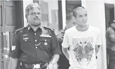  ??  ?? Liew being escorted by a policeman at the court house.