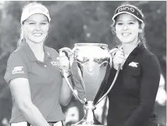  ?? — AFP photo ?? Brooke Henderson with the champions trophy and her sister &amp; caddie, Brittany, following the final round of the CP Womens Open at the Wascana Country Club in Regina, Canada.