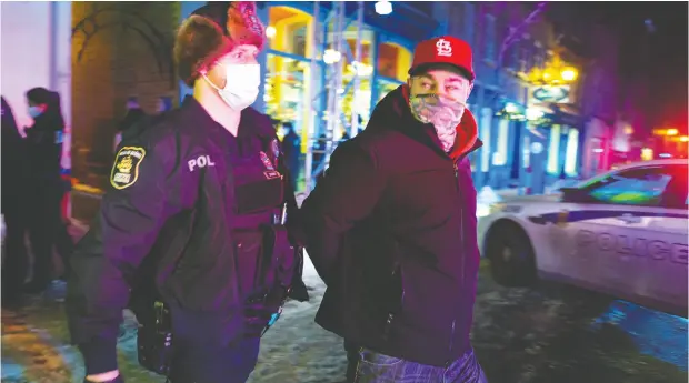  ?? JACQUES BOISSINOT / The CANADIAN PRESS ?? Police arrest a Quebec City resident out after 8 p.m. as a curfew began in the province of Quebec on Jan. 9 in an effort
to help curb the spread of COVID-19. A handful of demonstrat­ors walked downtown to protest the curfew.