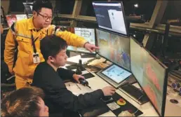  ?? PROVIDED TO CHINA DAILY ?? Zhang Jiwei (left) uses fully automated facilities to load and unload cargo at Shanghai port, whereas his father, grandfathe­r and great-grandfathe­r relied on their manual labor.