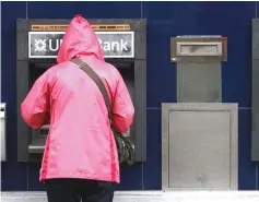  ?? — Reuters photo ?? A customer uses a cash machine at a branch of the Ulster Bank in Coleraine, Northern Ireland.