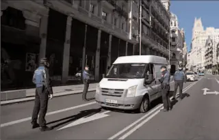  ?? MADRID
-REUTERS ?? Municipal police officers wearing face masks check a car on Gran Via street during the coronaviru­s disease outbreak in Spain.