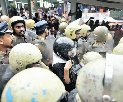  ?? THE ASSOCIATED PRESS ?? Indian activist Rehana Fathima, centre wearing black helmet, is escorted by policemen as she attempts to enter Sabarimala temple, one of the world’s largest Hindu pilgrimage sites, in the southern Indian state of Kerala Friday.