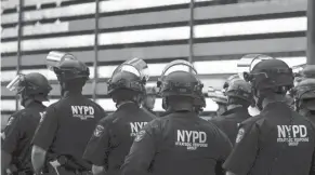  ?? TIMOTHY A. CLARY/AFP VIA GETTY IMAGES ?? New York police officers watch demonstrat­ors on June 1. The city is one of three singled out for their response to unrest.