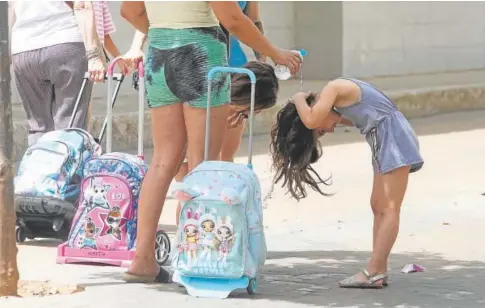  ?? ?? Una madre refresca a su hija a la salida de un colegio en Córdoba // RAFAEL CARMONA