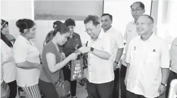  ??  ?? Dr Sim presents a free T-shirt to a hawker attending the dialogue session. At right is Chan.