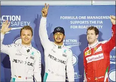  ??  ?? Mercedes AMG Petronas F1 Team’s British driver Lewis Hamilton (center), flashes the victory sign next to Mercedes AMG Petronas F1 Team’s German driver Nico Rosberg (left), and Ferrari’s German driver Sebastian Vettel after securing the pole position in the Bahrain Formula One Grand Prix following the qualifying session atthe Sakhir circuit in Manama on April 2, a day ahead of the race. (AFP)