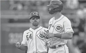  ?? SAM GREENE/THE ENQUIRER ?? Cincinnati Reds first base coach Collin Cowgill talks with catcher Tyler Stephenson, whose groundout led to a run against the Pirates on opening day.