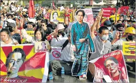  ?? REUTERS ?? Anti-coup protesters in Yangon hold placards with the image of Aung San Suu Kyi.