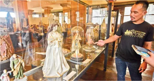  ?? SUNSTAR FOTO / AMPER CAMPAÑA ?? TREASURES. Fr. Brian Brigoli shows visitors some of the items that are on display in the Archdioces­an Museum of Cebu.