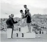  ??  ?? Harold Nelson of New Zealand accepting gold for the six-mile event alongside Andrew Forbes of Scotland, left, and Noel Taylor of New Zealand, right, at the 1950 games.