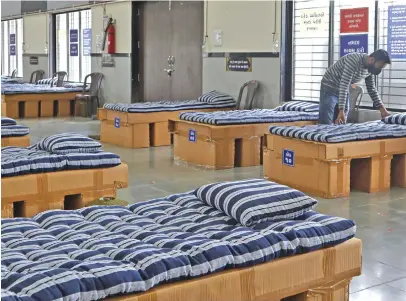  ??  ?? A man adjusts a bed inside the office of Indian businessma­n Kadar Shaikh, who converted his business premises into a coronaviru­s ward for the poor after recovering from the illness.