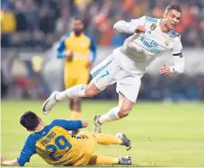  ??  ?? Vuelo. El jugador del Real Madrid Cristiano Ronaldo cae ante la marca de Praxitelis Vouros, del Apoel de Nicosia