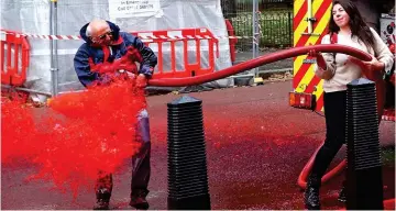  ??  ?? Splash back: One protester is covered in red water as another grapples with hose