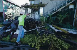  ?? PHOTOS BY GERALD HERBERT — THE ASSOCIATED PRESS ?? Caleb Cormier moves debris Saturday in Lake Charles, La., after Hurricane Delta moved through. Delta hit as a Category 2 hurricane with top winds of 100mph.