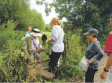  ??  ?? Members of a Classic Journeys walking tour group in Swinbrook, England, climb one of many stiles, or fences, along a walking path through pastures. Nancy Nathan, Special to The Washington Post