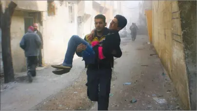  ?? AP PHOTO ?? This photo released on Saturday by the Syrian Civil Defense group known as the White Helmets, shows members of the Syrian Civil Defense group carrying a young man who was wounded during airstrikes and shelling by Syrian government forces, in Ghouta, a...