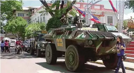 ?? AGENCY PIX ?? Residents walking past a military armoured personnel carrier yesterday following President Rodrigo Duterte’s declaratio­n of martial law in Davao City, Mindanao Island, on Tuesday.